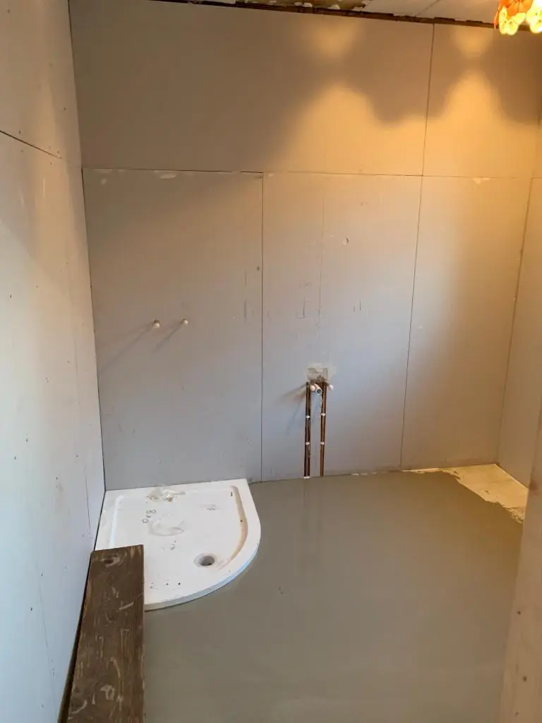During the build: boarded walls, first-fix copper pipework and the shower tray set out