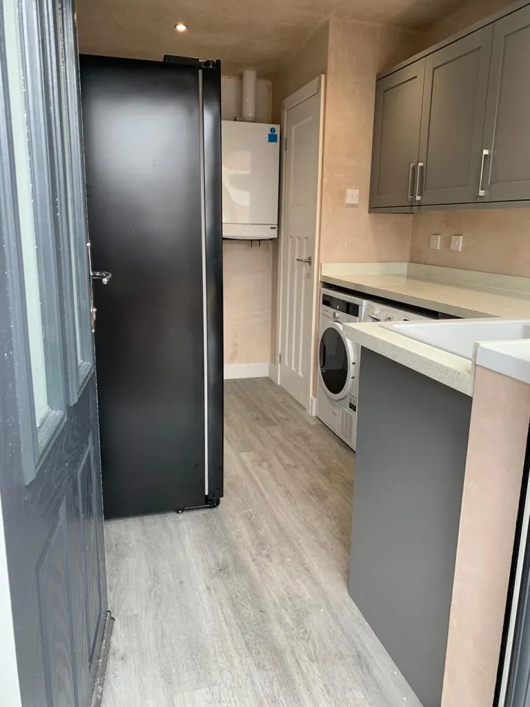 Galley utility with grey shaker cabinets, black american-style fridge and concealed boiler