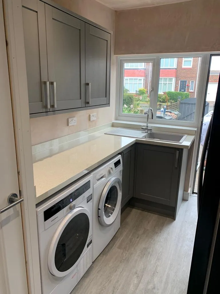 Utility room with grey shaker units, sparkle quartz worktop and stacked laundry appliances